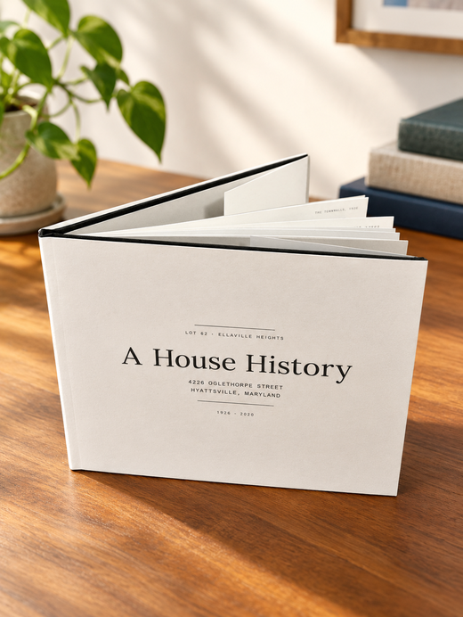 A hardcover Deed & Dwelling house history book, titled 'A House History,' standing on a table